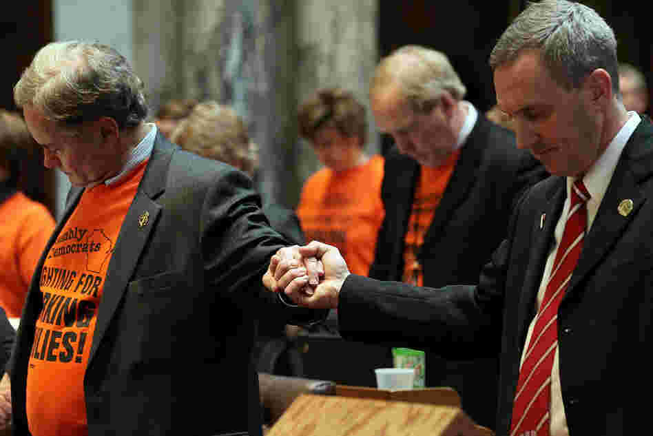 Democratic Assembly Minority Leader Peter Barca (left) holds hands with a Republican lawmaker during a prayer at the start of the Assembly session.  