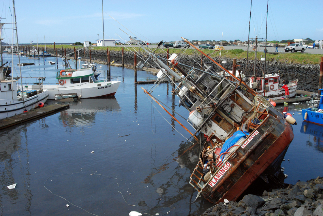 A fishing boat lies on its side in shallow water in the boat basin at Crescent City, Calif., after a tsunami surge withdrew Friday.