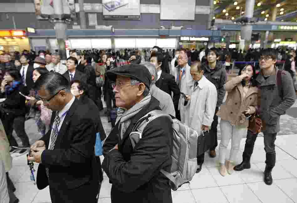 Train passengers wait at Tokyo's Shinagawa station. Train service and other public transportation was halted following the earthquake. 