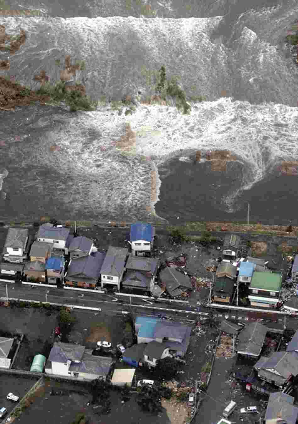 A tsunami approaches seashore houses in Kita Ibaraki, Ibaraki prefecture, northeast of Tokyo. 