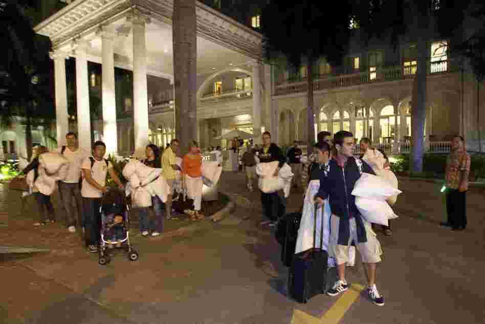 Hotel guests from the Moana Surfrider evacuate early Friday in Honolulu. The National Weather Service issued tsunami warnings for 50 countries and territories. 