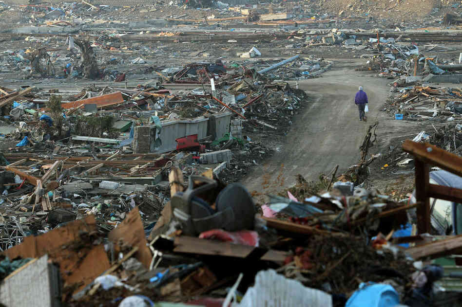 A man walks along a road lined with debris at Onagawa town in Miyagi prefecture. 