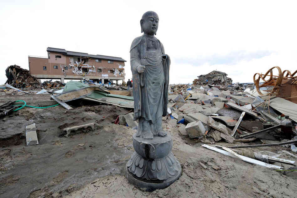 A religious statue stands amid debris in a tsunami-devastated area close to the seafront in Natori, Miyagi prefecture. 