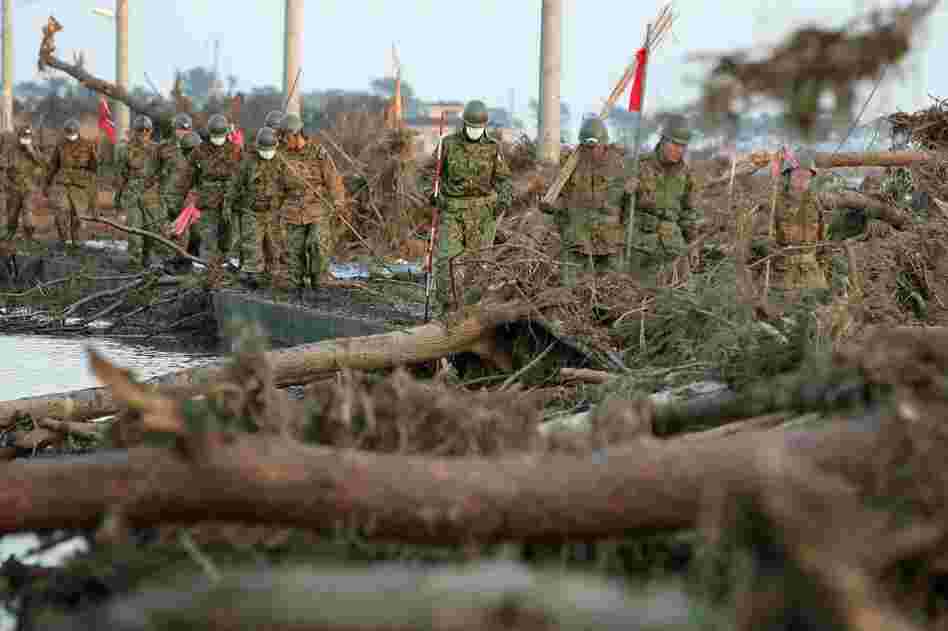 Members of the Japanese military walk through tsunami wreckage in Sendai, Japan on Sunday. 