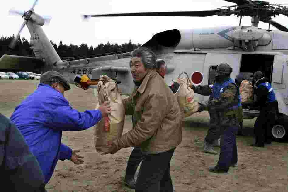 Rescuers and victims carry out bags of food aid from a helicopter in Yamada, northern Japan. 