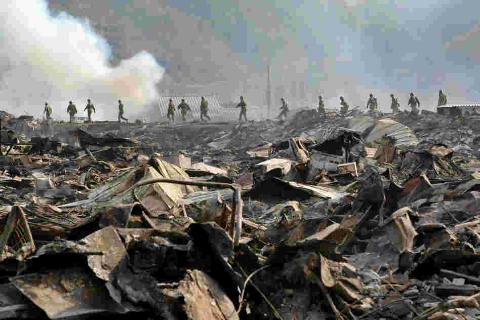 Members of the Japanese military walk through devastation to search for missing people at Otsuchi town in Iwate prefecture on Sunday. 