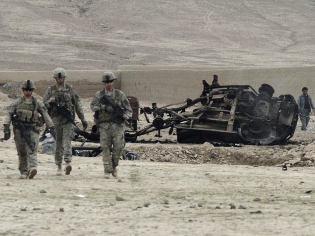 U.S. soldiers pass car wreckage after an explosion in Kandahar province, Afghanistan, February 2011.
