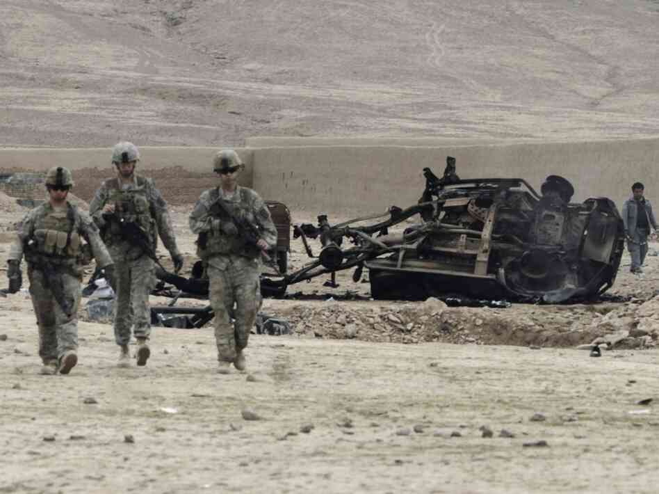 U.S. soldiers pass car wreckage after an explosion in Kandahar province, Afghanistan, February 2011.