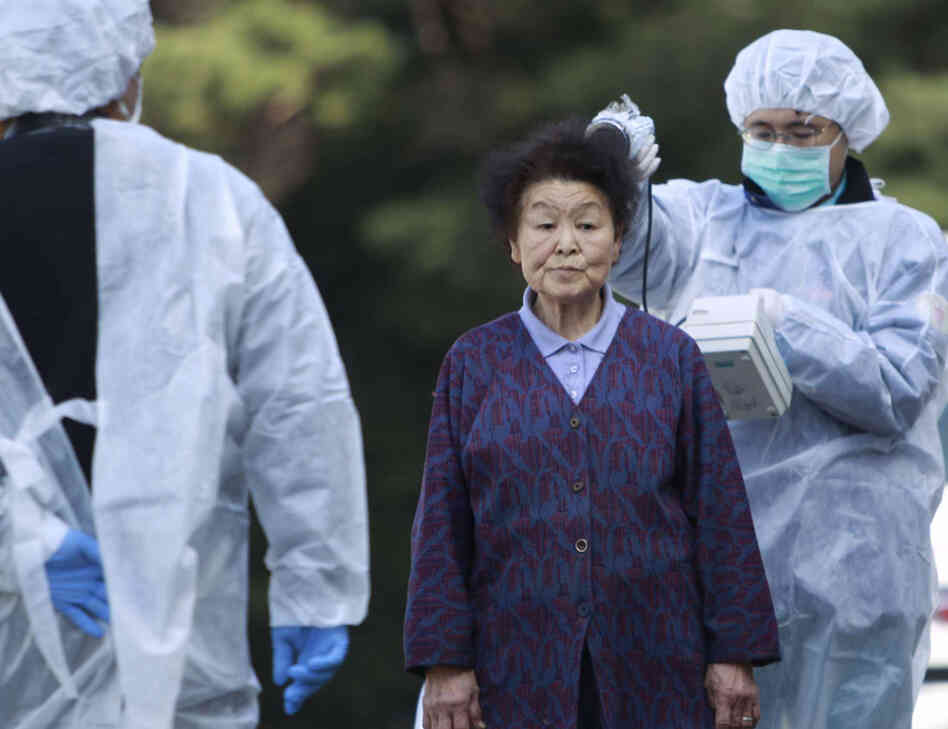 Officials check the level of radiation on a woman in Fukushima prefecture.