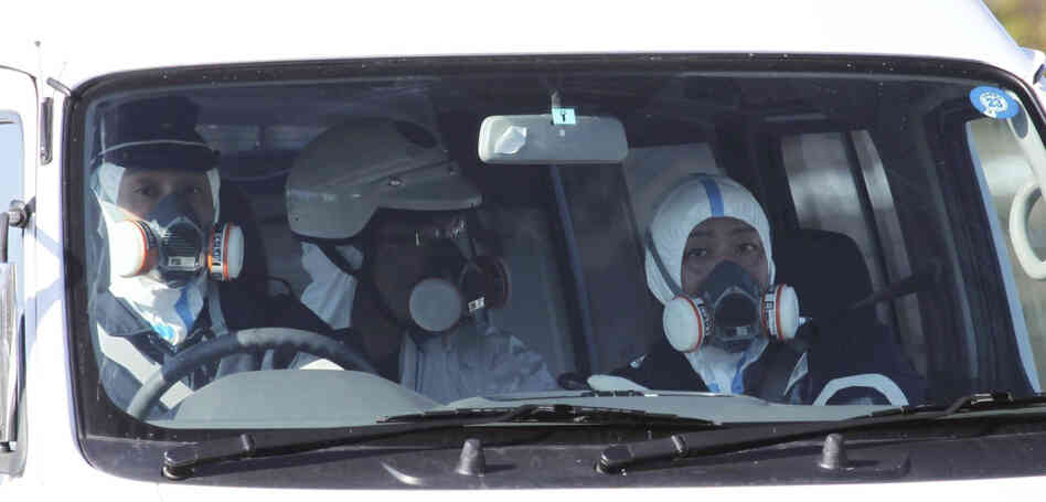 Police officers wear gas masks while on patrol in a vehicle at the Fukushima nuclear power plant on March 12. Experts are concerned about the safety of the nuclear workers, but they say that so far, there's no risk for others in Japan or in the U.S.