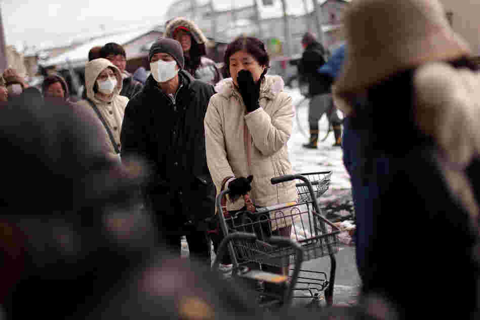 A woman waits in a line outside a grocery store in Ichinoseki. 