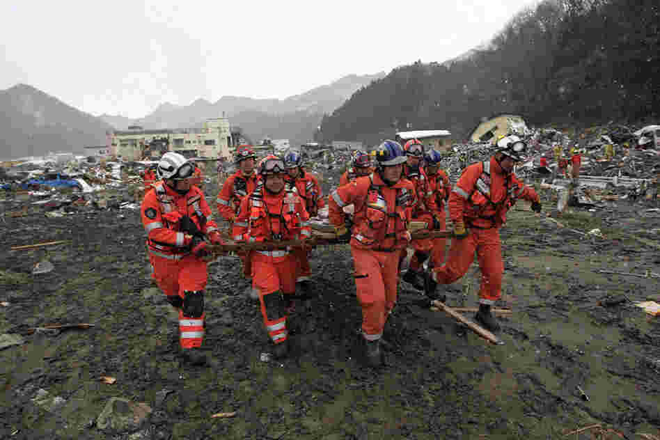 Members of a British search-and-rescue team carry a body removed from a destroyed house in Kamaishi, Japan. The official death toll climbed above 5,300 on Thursday. 