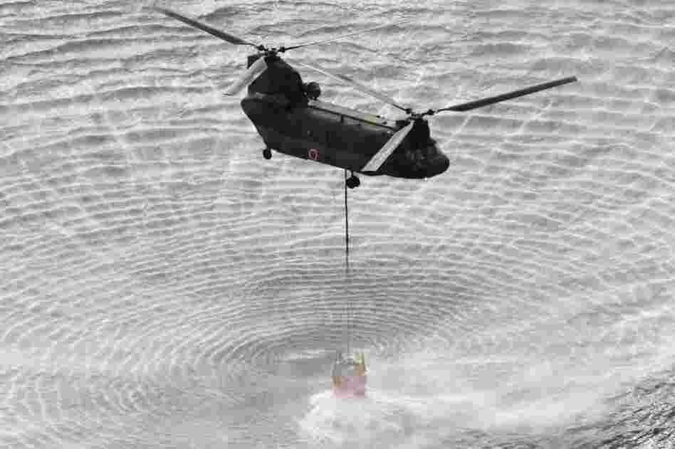 A military helicopter scoops water off Japan's northeast coast on its way to the Fukushima Dai-ichi nuclear power plant on Thursday, in an effort to cool overheated fuel rods inside the core. 