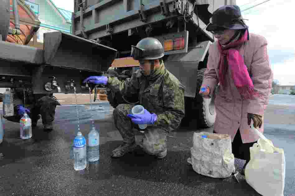 A Japanese soldier provides water for local residents in Kesennuma, Miyagi prefecture. 