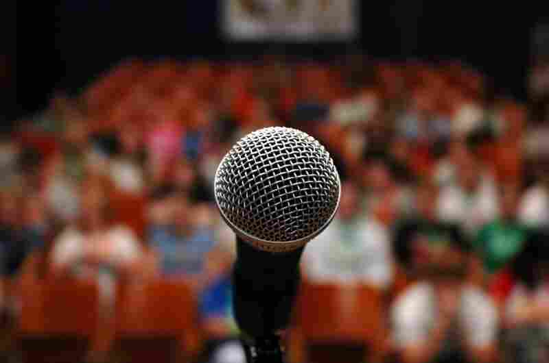 A microphone in front of an audience. A microphone in front of an audience.