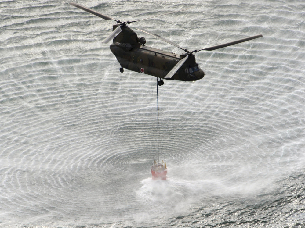 A Self-Defense Forces helicopter scoops water off Japan's northeast coast on the  way to the Fukushima Dai-ichi nuclear power plant Thursday morning. Helicopters  are dumping water on a stricken reactor to cool overheated fuel rods inside the  core.