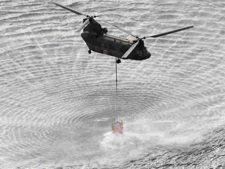 A Self-Defense Forces helicopter scoops water off Japan's northeast coast on the  way to the Fukushima Dai-ichi nuclear power plant Thursday morning. Helicopters  are dumping water on a stricken reactor to cool overheated fuel rods inside the  core.