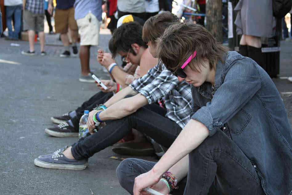 Showgoers resting on a curb in between sets. 