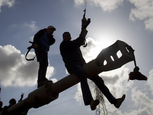 A Libyan rebel shoots in the air Sunday as he celebrates with others on a tank belonging to forces loyal to leader Moammar Gadhafi, on the outskirts of Benghazi, eastern Libya.