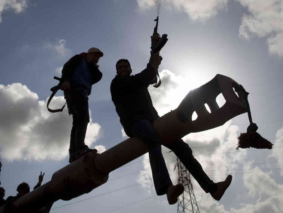 A Libyan rebel shoots in the air Sunday as he celebrates with others on a tank belonging to forces loyal to leader Moammar Gadhafi, on the outskirts of Benghazi, eastern Libya.