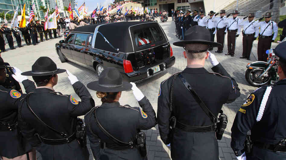 Police officers salute as a hearse carrying the body of one of two slain Miami-Dade police officers arrives for a memorial service in Miami in January. Officers Amanda Haworth and Roger Castillo were killed while serving an arrest warrant.