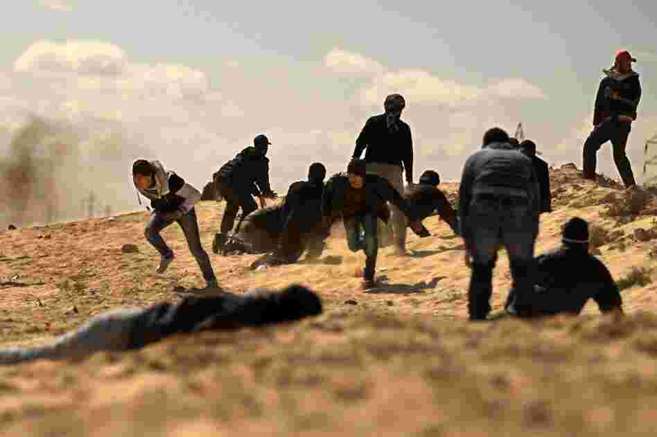 Rebels duck for cover as they come under tank fire from Gadhafi's forces on the outskirts of Ajdabiya as rag-tag rebel forces massed for a second day to try to attack government forces that have encircled the town. 