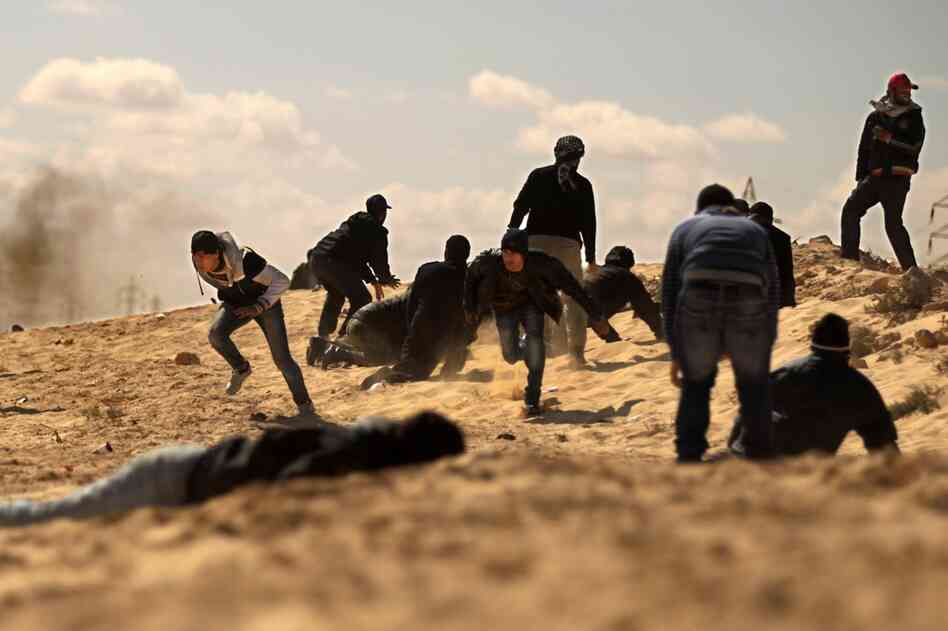 Rebels duck for cover as they come under tank fire from Gadhafi's forces on the outskirts of Ajdabiya as rag-tag rebel forces massed for a second day to try to attack government forces that have encircled the town. 