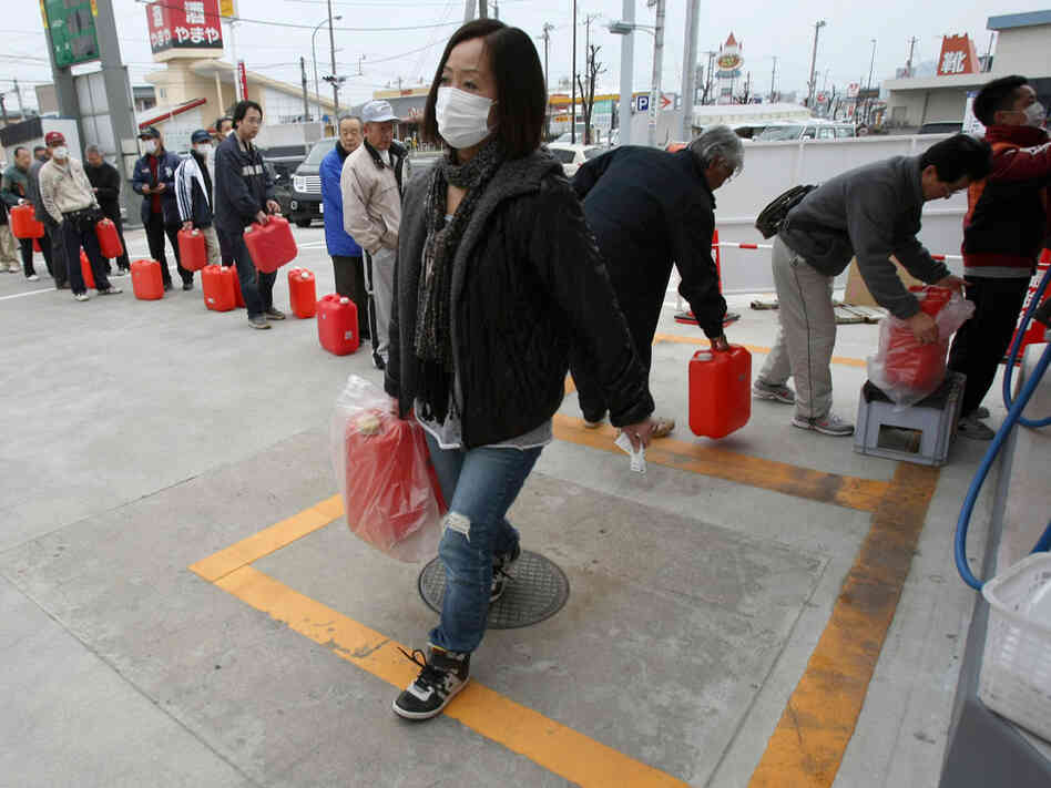 A woman carries fuel as lines of people wait with hopes of filling containers in Fukushima city on March 20. A woman carries fuel as lines of people wait with hopes of filling containers in Fukushima city on March 20.