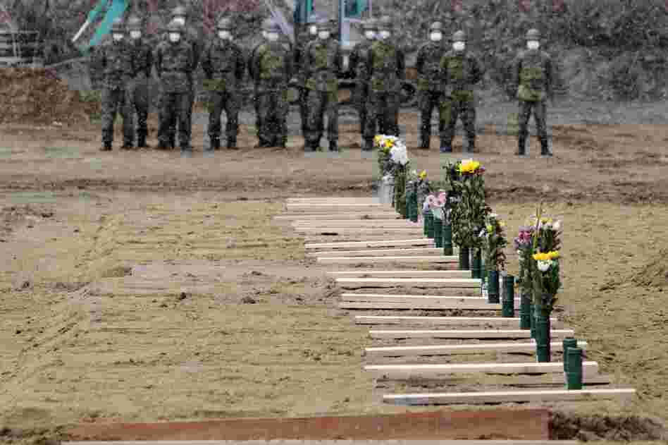 Japan Ground Self Defense Force troops stand near grave sites at a burial ceremony for the March 11 tsunami victims in Higashimatsushima city, Miyagi prefecture. 