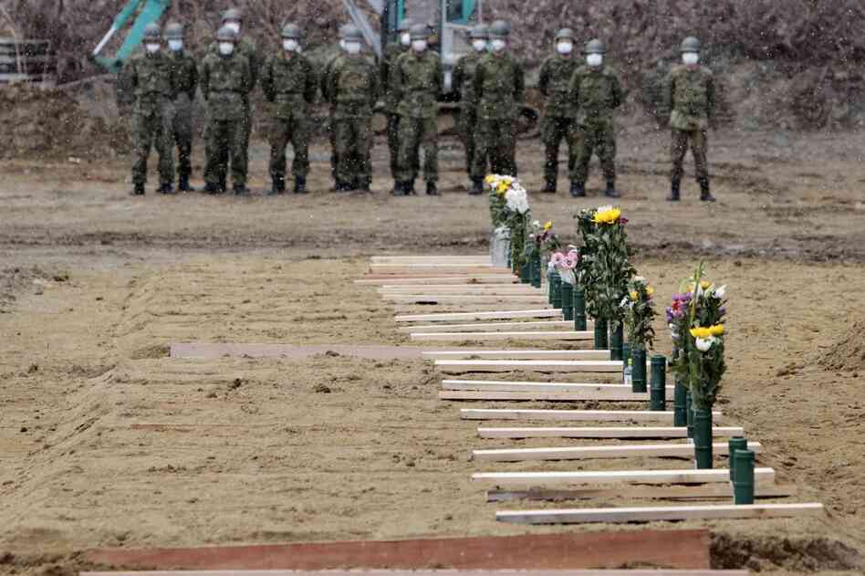 Japan Ground Self Defense Force troops stand near grave sites at a burial ceremony for the March 11 tsunami victims in Higashimatsushima city, Miyagi prefecture. 