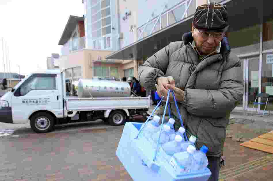 A man carries bottles of water after visiting a water tank in Urayasu, Chiba prefecture, near Tokyo. A spike in radiation levels in Tokyo tap water spurred new fears about food safety as rising black smoke forced another evacuation of workers trying to stabilize Japan's radiation-leaking nuclear plant. 