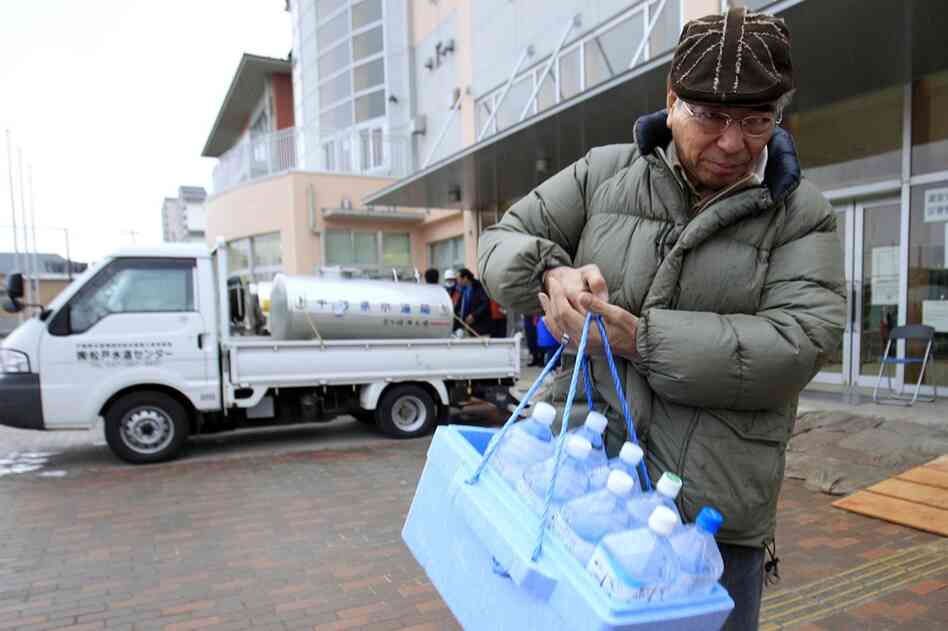 A man carries bottles of water after visiting a water tank in Urayasu, Chiba prefecture, near Tokyo. A spike in radiation levels in Tokyo tap water spurred new fears about food safety as rising black smoke forced another evacuation of workers trying to stabilize Japan's radiation-leaking nuclear plant. 