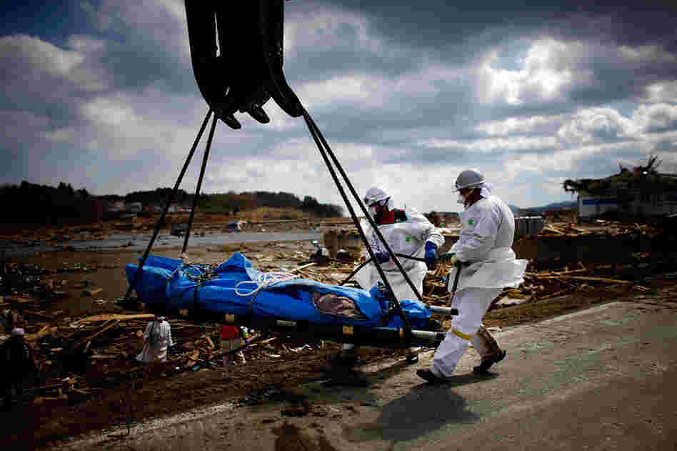 Workers use a the bucket of a crane to lift a body out of the sea of wreckage in the tsunami-damaged city of Rikuzentakata, Iwate prefecture. The tsunami and earthquake has now left close to 10,000 people dead and thousands more missing, with entire communities along the northeast coast swept away. 