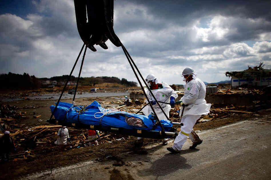 Workers use a the bucket of a crane to lift a body out of the sea of wreckage in the tsunami-damaged city of Rikuzentakata, Iwate prefecture. The tsunami and earthquake has now left close to 10,000 people dead and thousands more missing, with entire communities along the northeast coast swept away. 