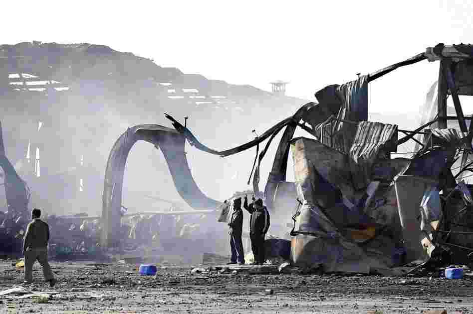 People stand in front of the wreckage of the Boussetta Libyan navy base the day after it was bombarded around six miles east of Tripoli center. 