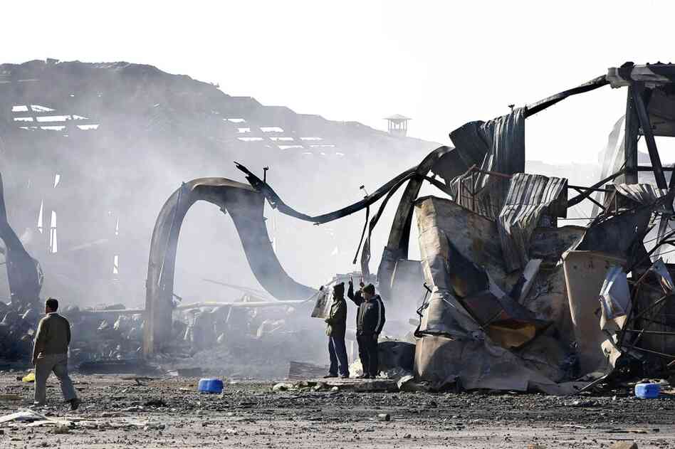 People stand in front of the wreckage of the Boussetta Libyan navy base the day after it was bombarded around six miles east of Tripoli center. 