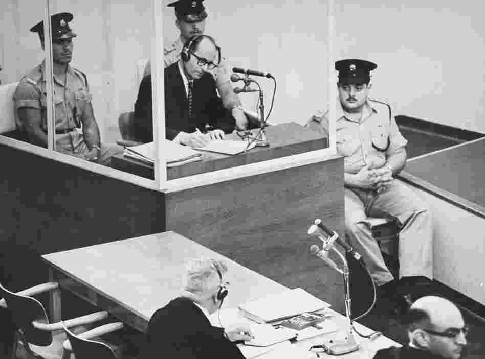 Defendant Adolf Eichmann takes notes during his trial in Jerusalem. The glass booth in which Eichmann sat was erected to protect him from assassination. Defendant Adolf Eichmann takes notes during his trial in Jerusalem. The glass booth in which Eichmann sat was erected to protect him from assassination.