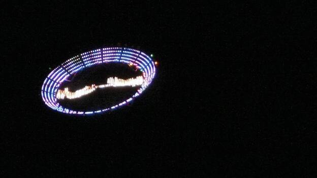 US plastic artist Peter Coffin's "Flying Saucer" — a 7-meter, LED-studded, SMS-controlled flying saucer and lifted by a helicopter — overflies Ipanema beach, on May 23, 2009, in Rio de Janeiro, Brazil.