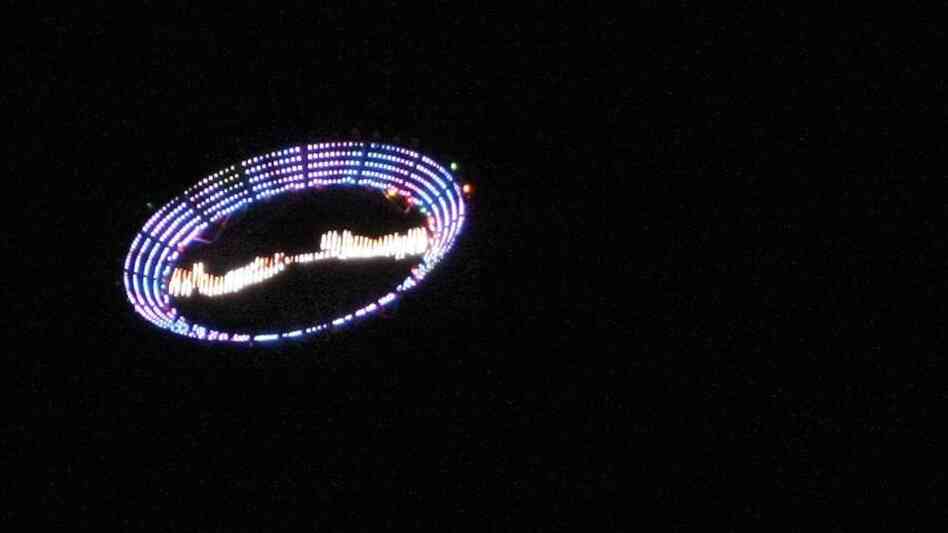 US plastic artist Peter Coffin's "Flying Saucer" — a 7-meter, LED-studded, SMS-controlled flying saucer and lifted by a helicopter — overflies Ipanema beach, on May 23, 2009, in Rio de Janeiro, Brazil.
