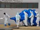 Officers in radiation protection suits hold a blue sheet over patients who were exposed to radiation at the Fukushima complex as they're taken to the hospital. Officers in radiation protection suits hold a blue sheet over patients who were exposed to radiation at the Fukushima complex as they're taken to the hospital.