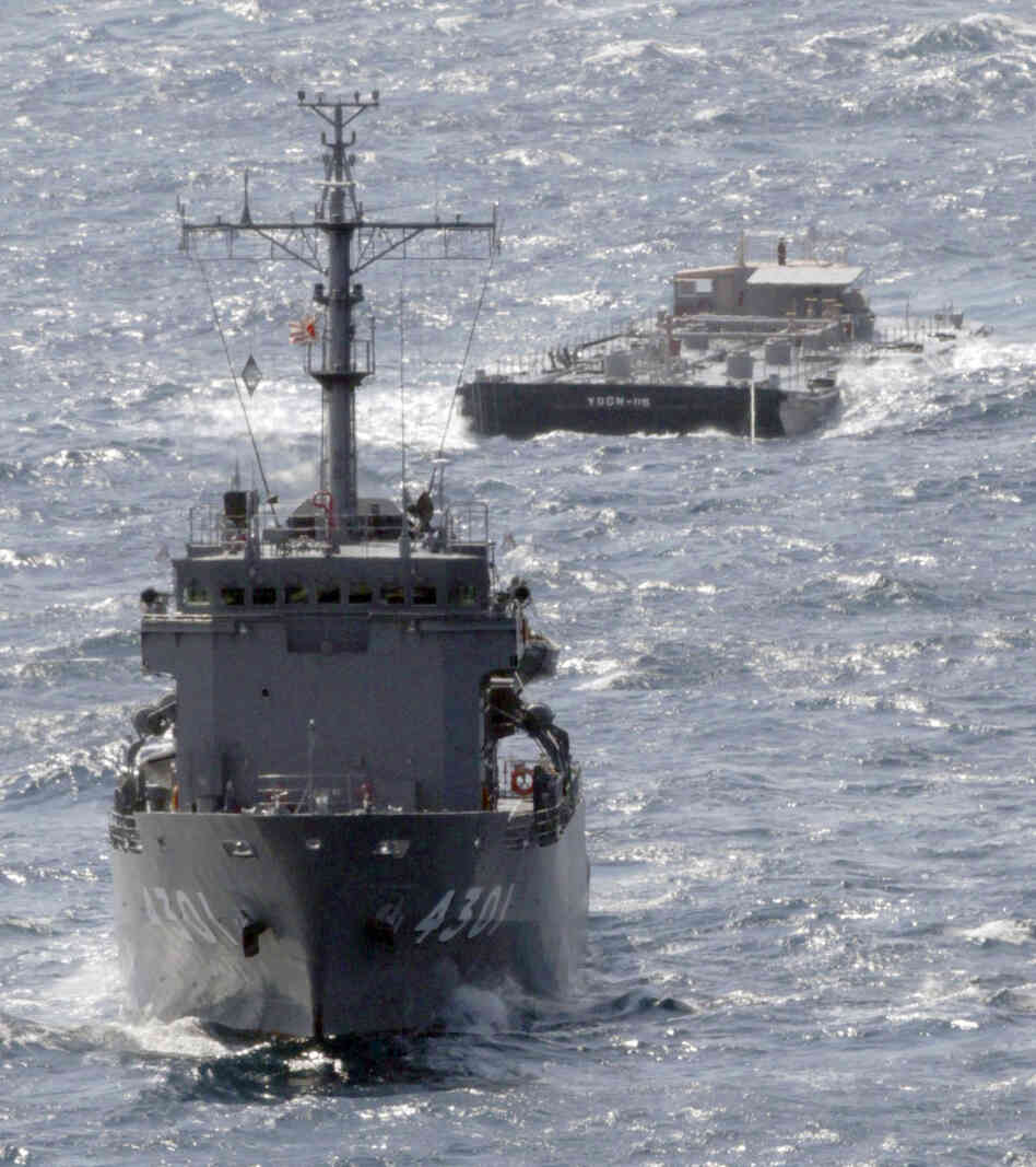 A U.S. Navy barge, back, is towed Saturday by a Japanese Maritime Self-Defense Force support ship off the coast of Japan. The barge is carrying 275,000 gallons of freshwater to support cooling efforts at the damaged Fukushima Dai-ichi nuclear power plant.