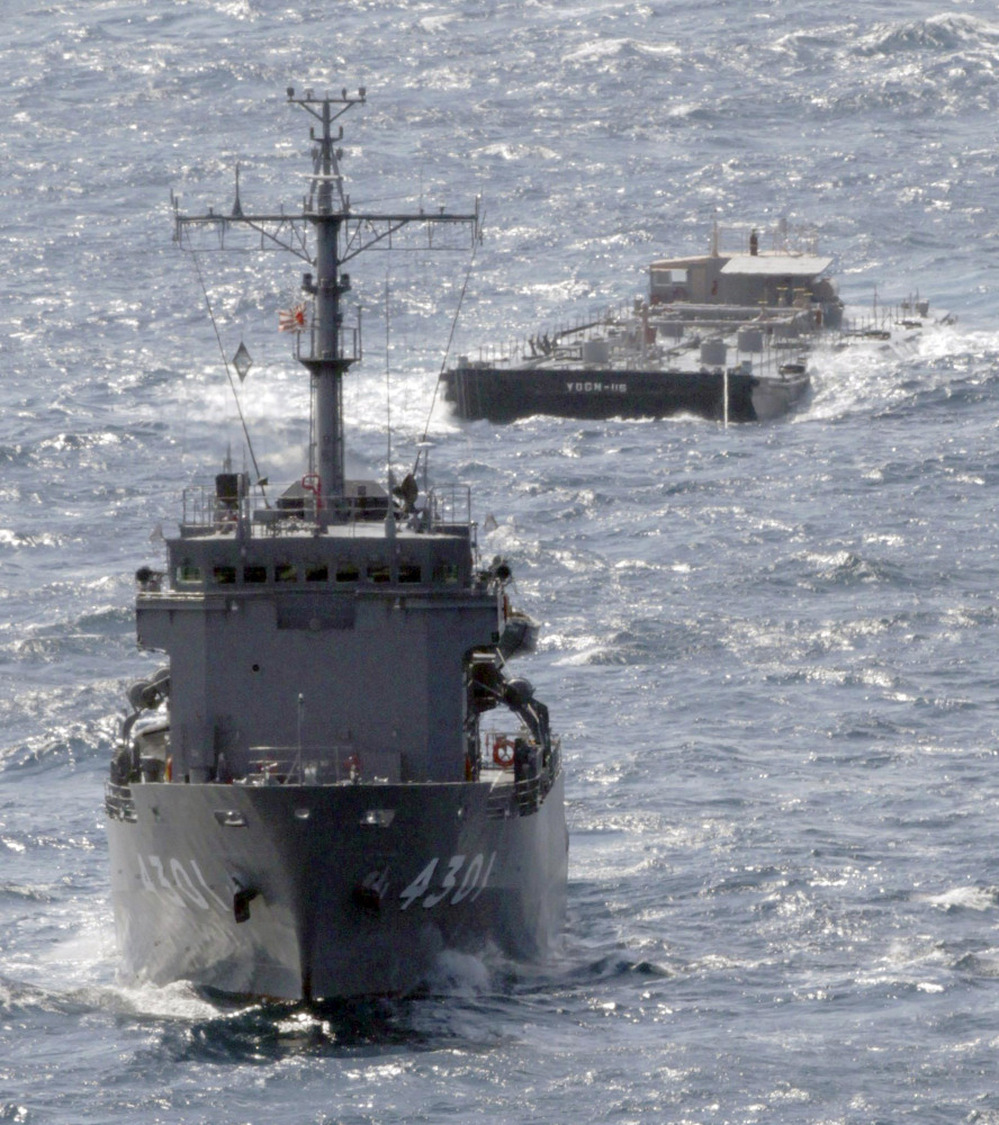 A U.S. Navy barge, back, is towed Saturday by a Japanese Maritime Self-Defense Force support ship off the coast of Japan. The barge is carrying 275,000 gallons of freshwater to support cooling efforts at the damaged Fukushima Dai-ichi nuclear power plant.