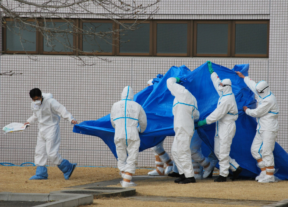 Japan Self-Defence Force officers in radiation protection suits hold a blue sheet over workers who were exposed this week to high levels of radiation at the Fukushima Dai-ichi plant.