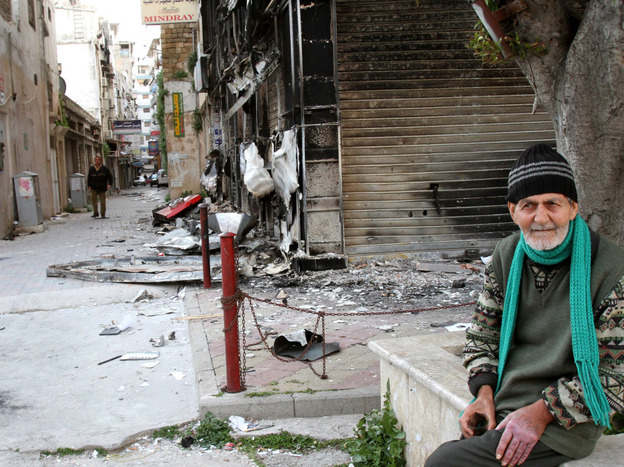 An elderly man sits near a burnt-out building in Latakia on March 27, 2011.