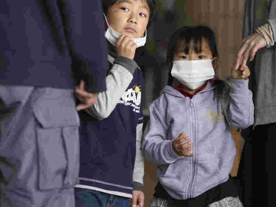 Children watch as their father is screened for radiation at a shelter in Fukushima prefecture, Japan. Plutonium is seeping from a damaged nuclear power plant into the soil outside, officials said Tuesday.