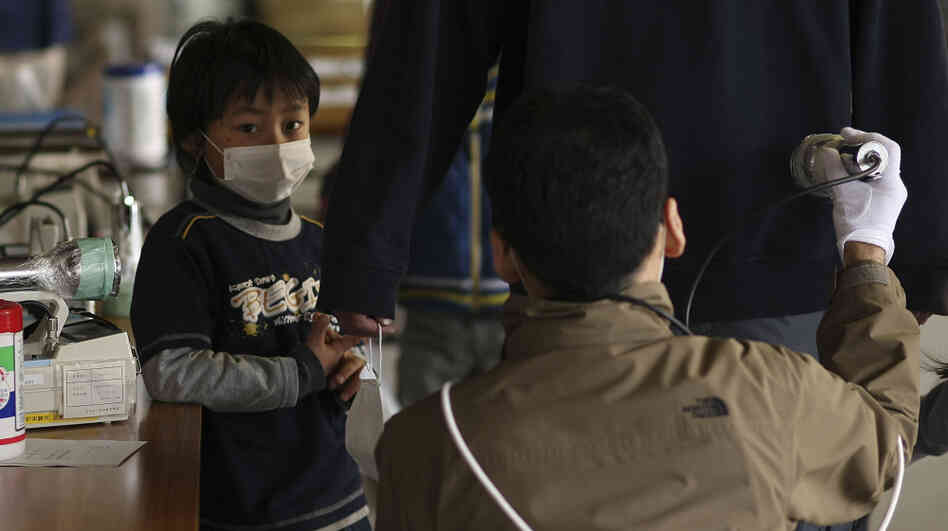 Earlier today (March 29, 2011), a boy watched his father being screened for radiation at a shelter in Fukushima prefecture.