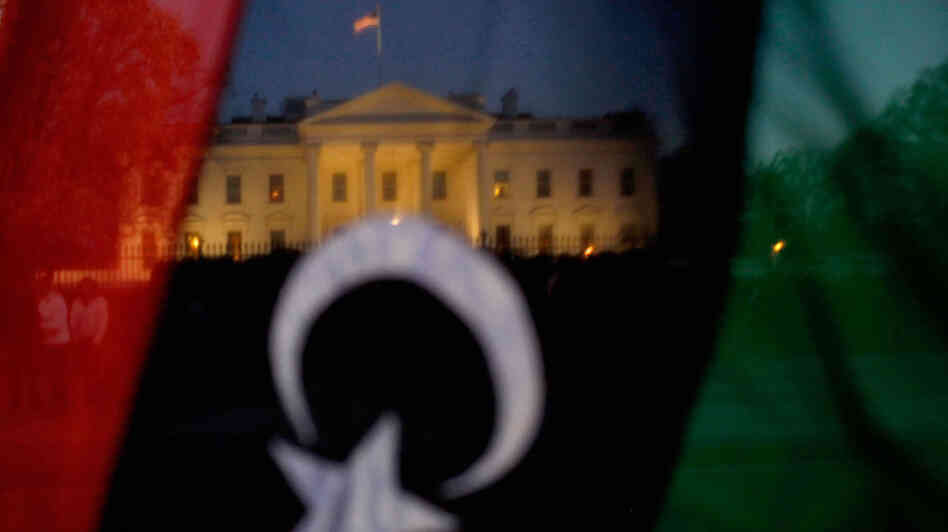 A demonstrator holds up a pre-Gadhafi Libyan flag while standing vigil in front of the White House on March 28. A demonstrator holds up a pre-Gadhafi Libyan flag while standing vigil in front of the White House on March 28.