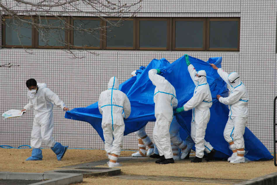 Japan Self-Defense Force officers in radiation protection suits hold a blue sheet over patients who were exposed to high levels of radiation at the Fukushima Dai-ichi nuclear power plant on March 25. A team of experts at Japan's National Institute of Radiological Sciences have helped treat injured workers.