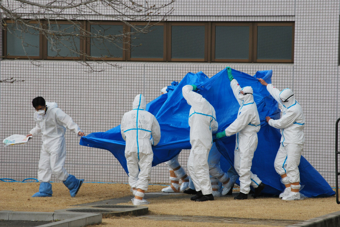 Japan Self-Defense Force officers in radiation protection suits hold a blue sheet over patients who were exposed to high levels of radiation at the Fukushima Dai-ichi nuclear power plant on March 25. A team of experts at Japan's National Institute of Radiological Sciences have helped treat injured workers.