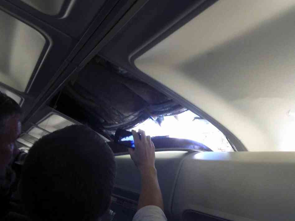In this photo provided by passenger Brenda Reese, an unidentified passenger takes photos with a cell phone of a hole in the cabin on a Southwest Airlines aircraft. In this photo provided by passenger Brenda Reese, an unidentified passenger takes photos with a cell phone of a hole in the cabin on a Southwest Airlines aircraft.